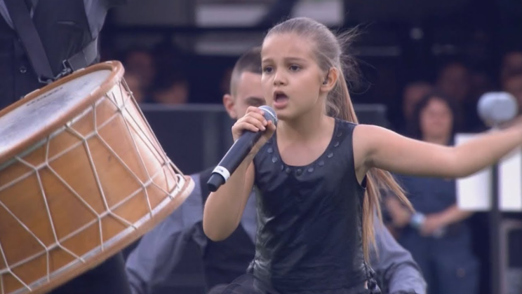 The talented little girl knocks down the house with a cover of Queen-Dropping “We Will Rock You”